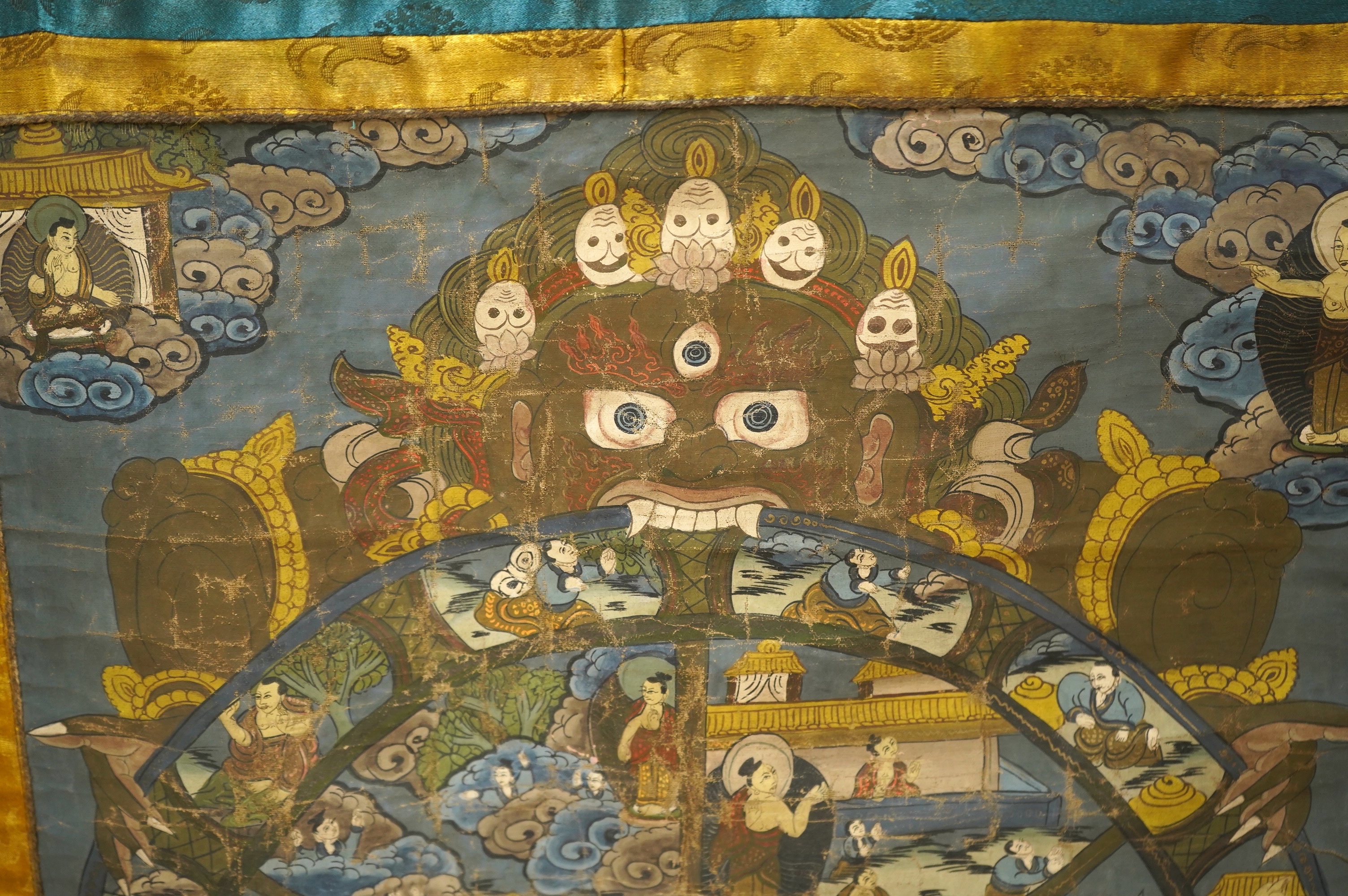 A 20th century Tibetan ‘Wheel of Life’ hand painted damask bordered Thangka, depicting the complex mandala of the circle of existence of beings in Buddhist philosophy, it depicts the teachings of Shakyamuni Buddha, showi